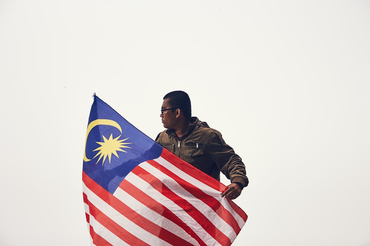 A man proudly holds the Malaysian flag, symbolizing patriotism and national pride.