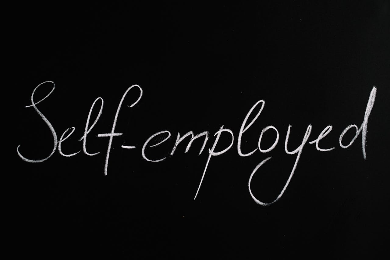 Handwritten 'Self-employed' in chalk on a blackboard background for business concepts.